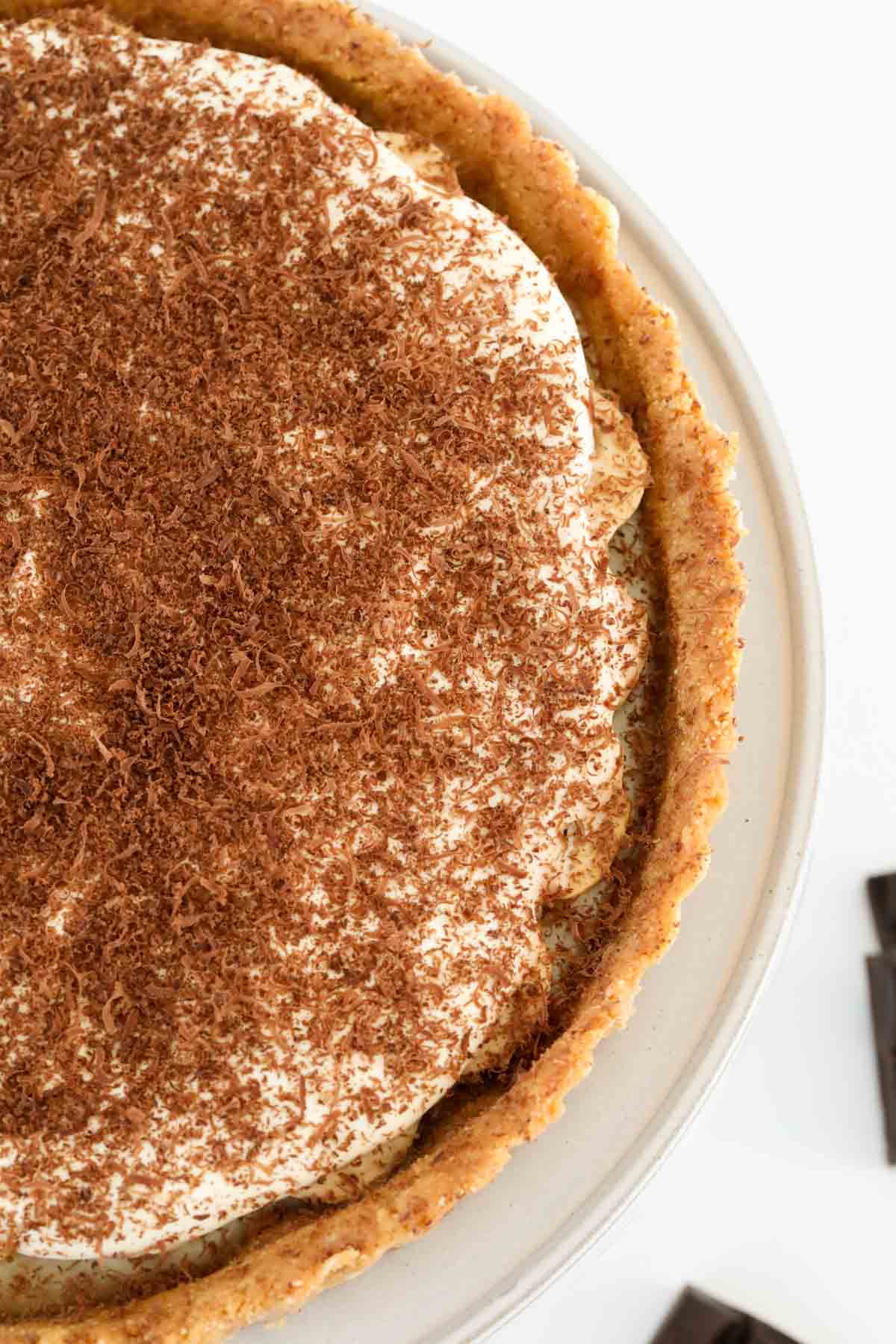 An overhead shot of a cream caramel pie, sprinkled with grated chocolate.