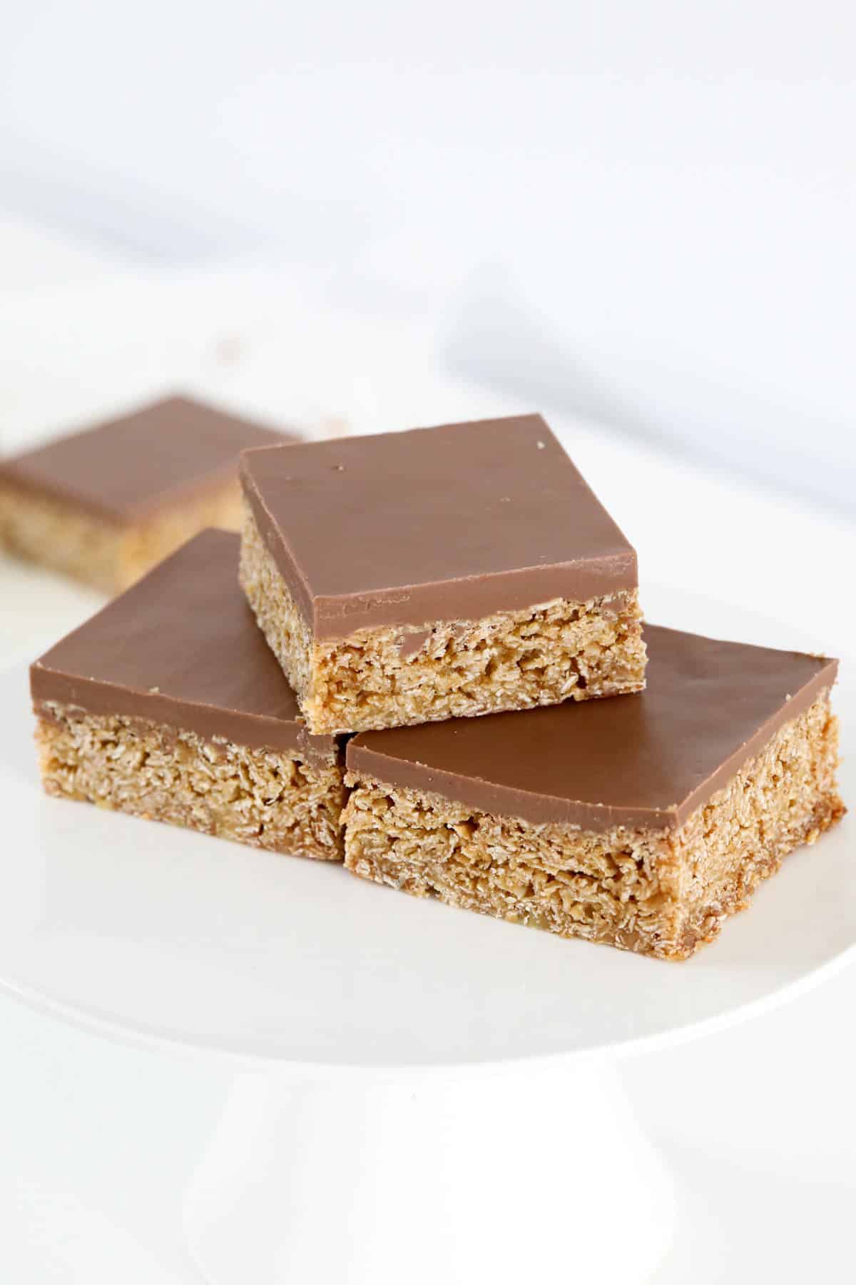 Chocolate topped slice cut into squares and served on a white plate.