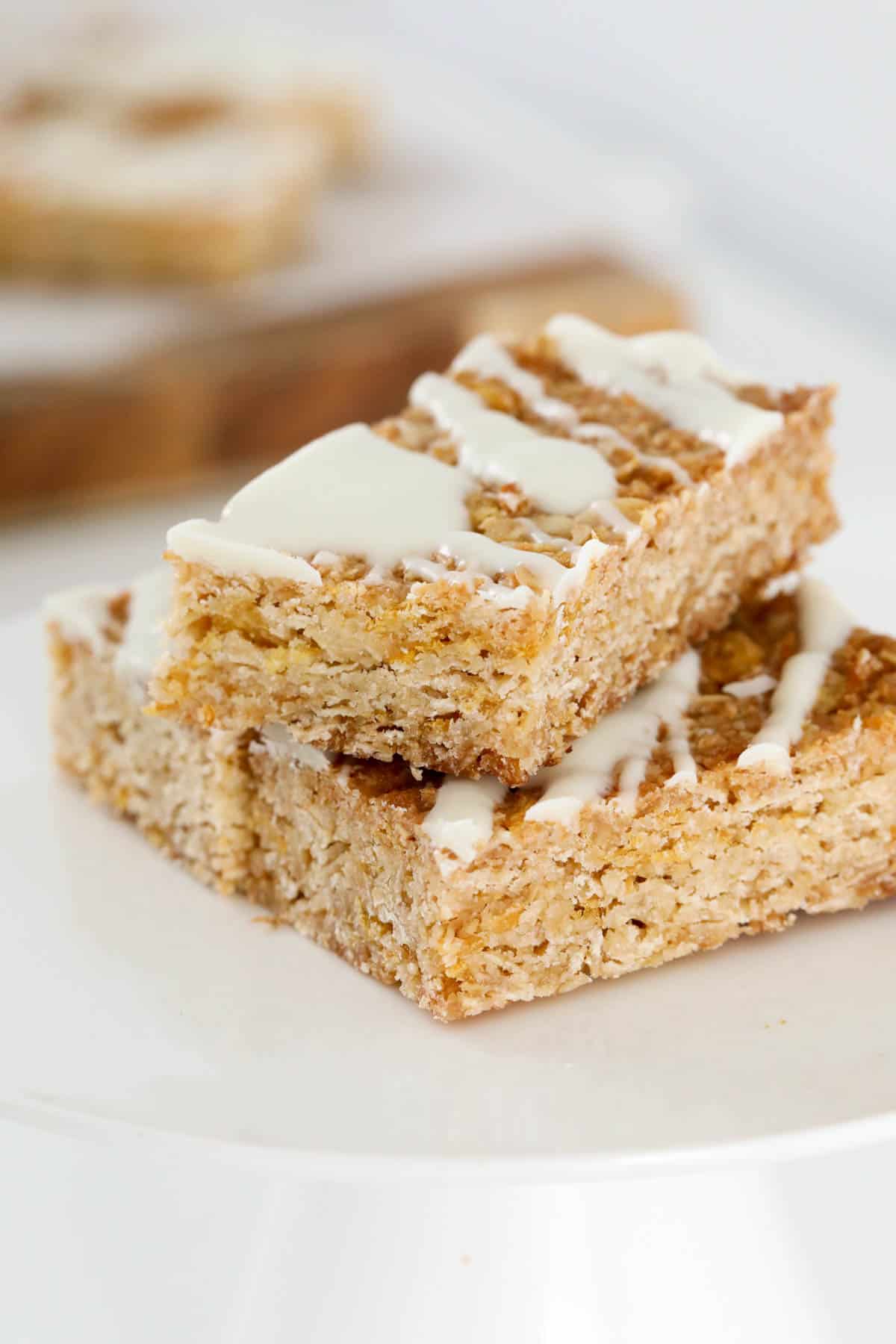 A close up of 3 pieces of cornflakes and oat slice drizzled with white chocolate on top.