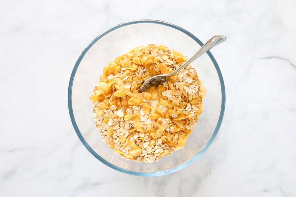 Corn Flakes, rolled oats and coconut mixed together in a glass bowl.