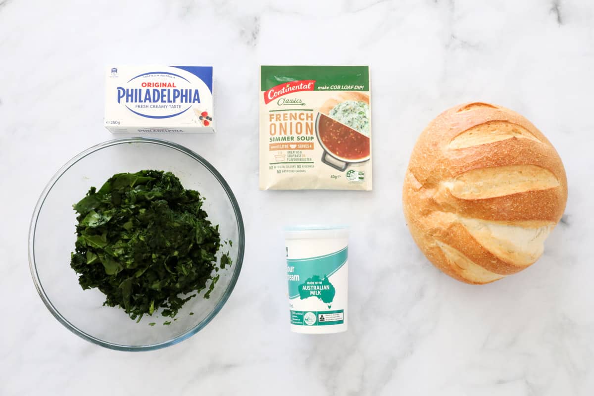 Igredients for making spinach cob loaf on a white marble background.