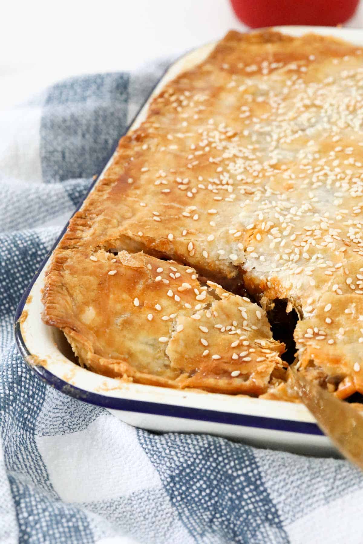 A golden puff pastry steak and mushroom pie in a baking tin.