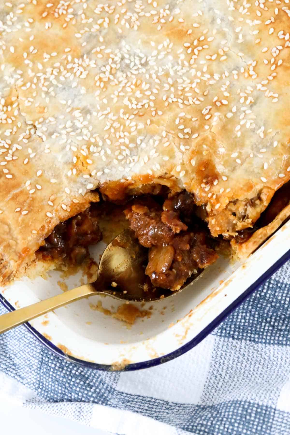 Steak and mushroom pie with a chunky beef filling, topped with golden flaky pastry in a baking dish. 