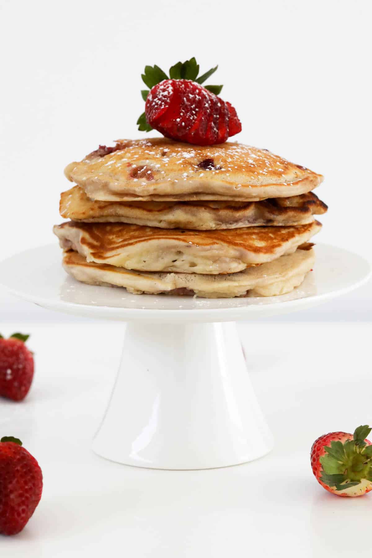Golden pancakes stacked on a white cake stand