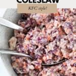 A bowl of creamy and colourful coleslaw with silver salad servers.