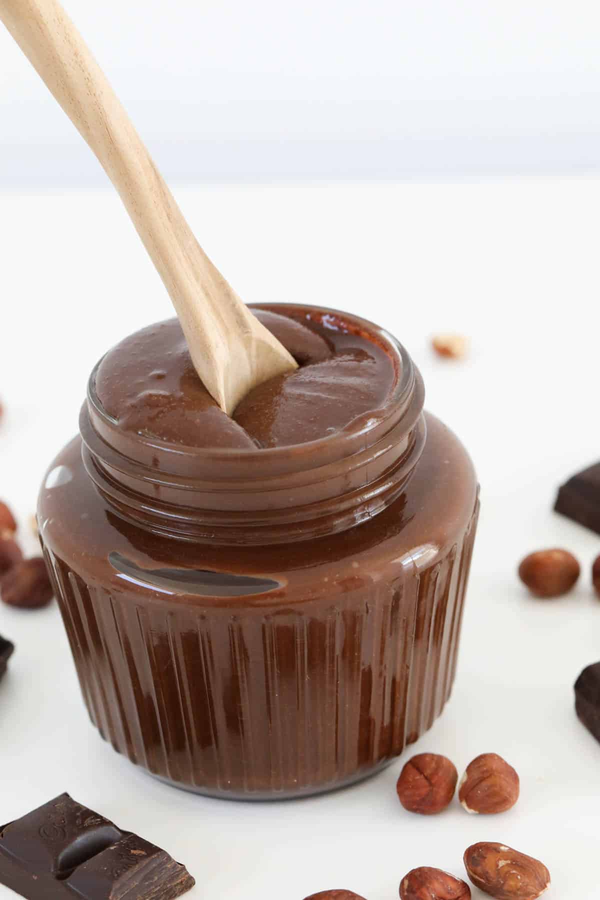 A spoon in a glass jar filled with homemade chocolate hazelnut spread.