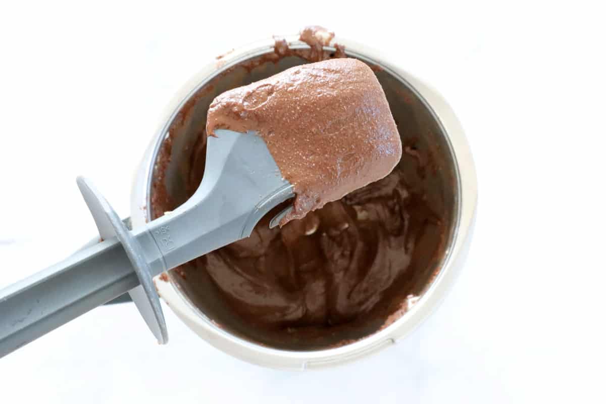 Chocolate hazelnut spread on a spatula held above a Thermomix bowl.