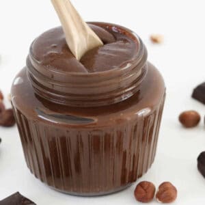 A spoon in a glass of homemade chocolate hazelnut spread.