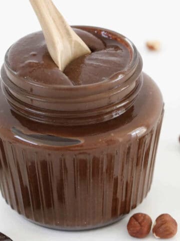 A spoon in a glass of homemade chocolate hazelnut spread.