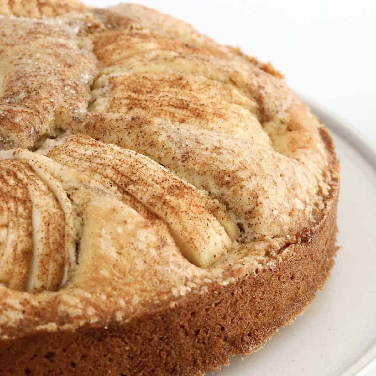 Apples and cinnamon on top of a round cake.