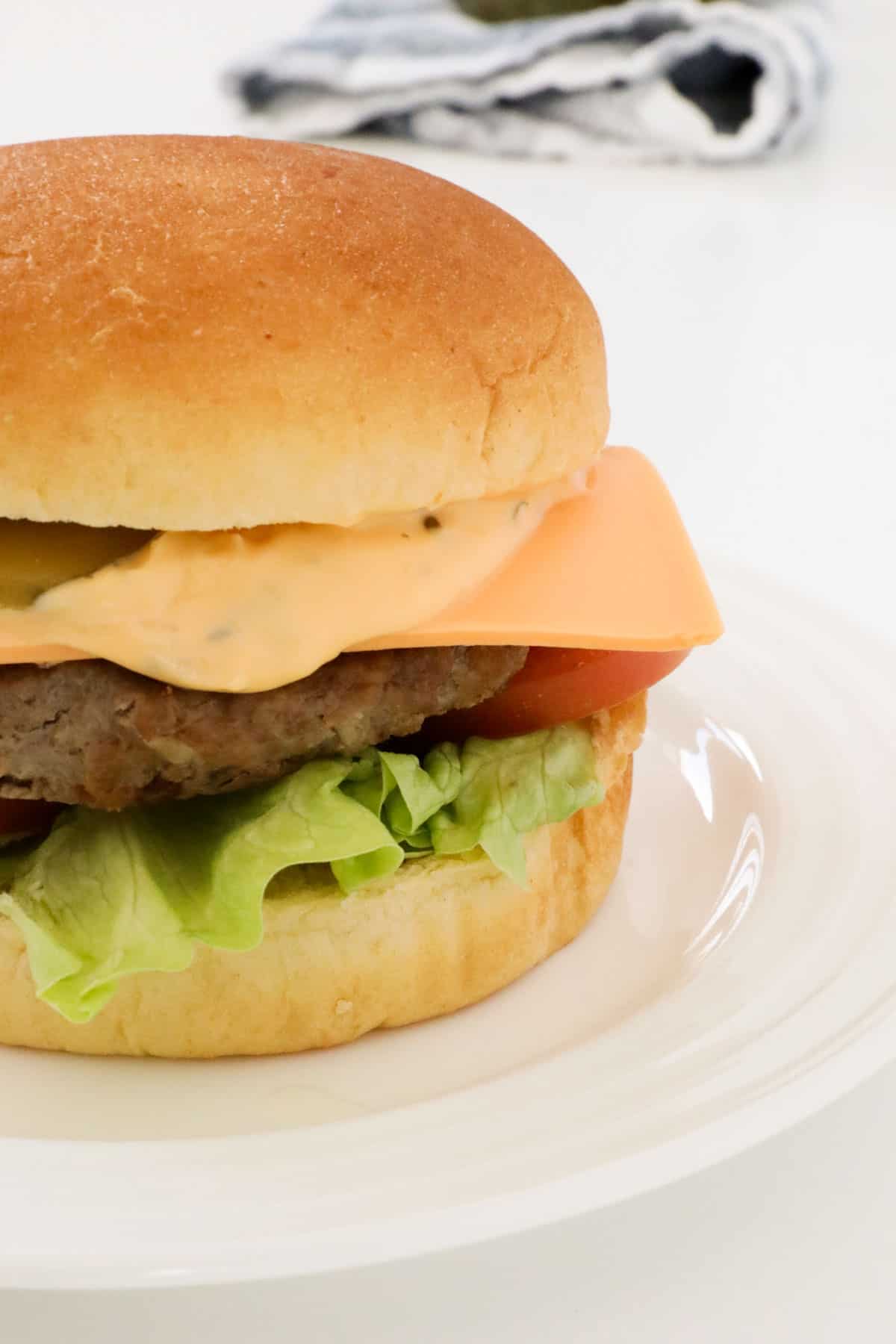 Lettuce, tomato, cheese and patty in a hamburger bun. 