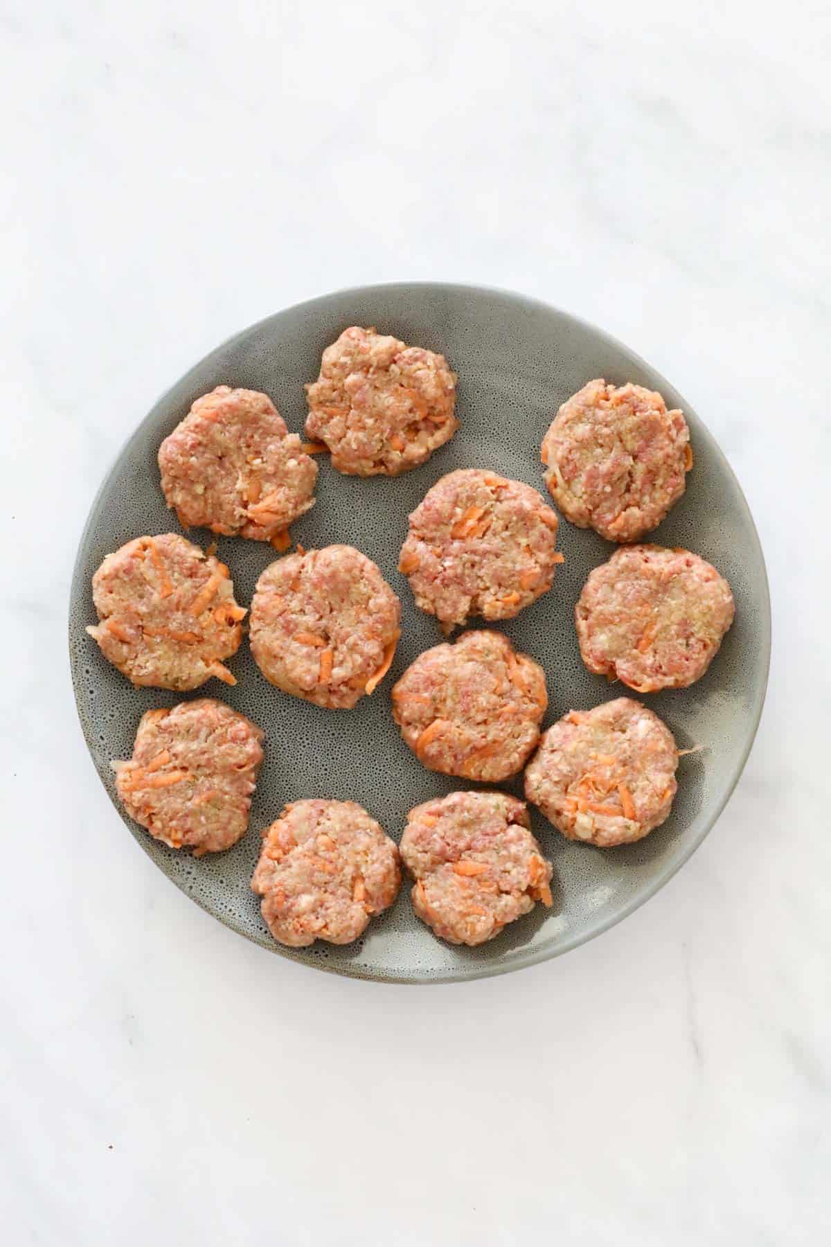 A plate of small uncooked mince patties.