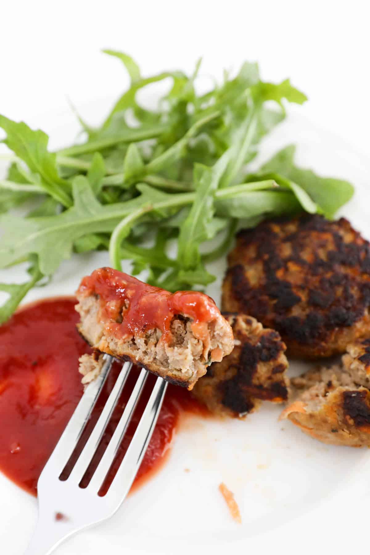 Tomato sauce on meat patties served with a rocket salad.
