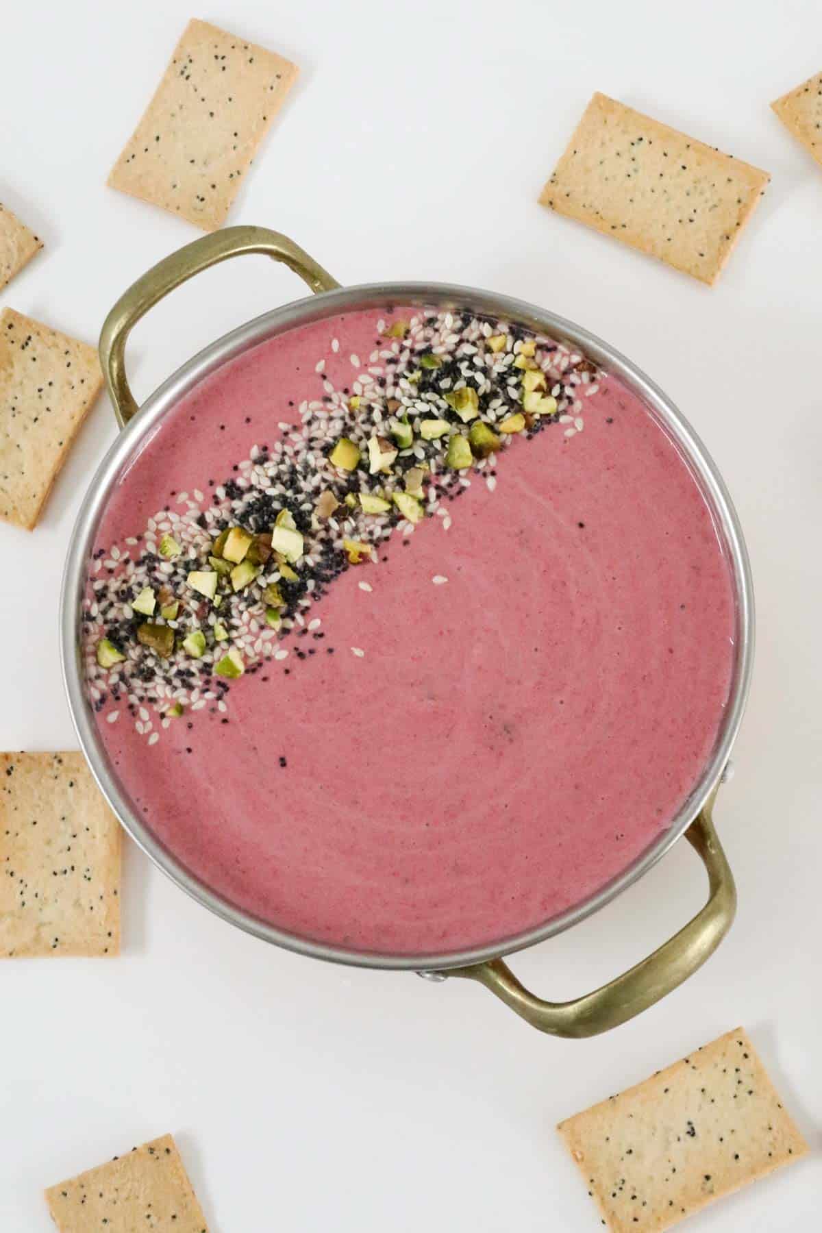 A beetroot dip in a bowl sprinkled with spicy dukkah.