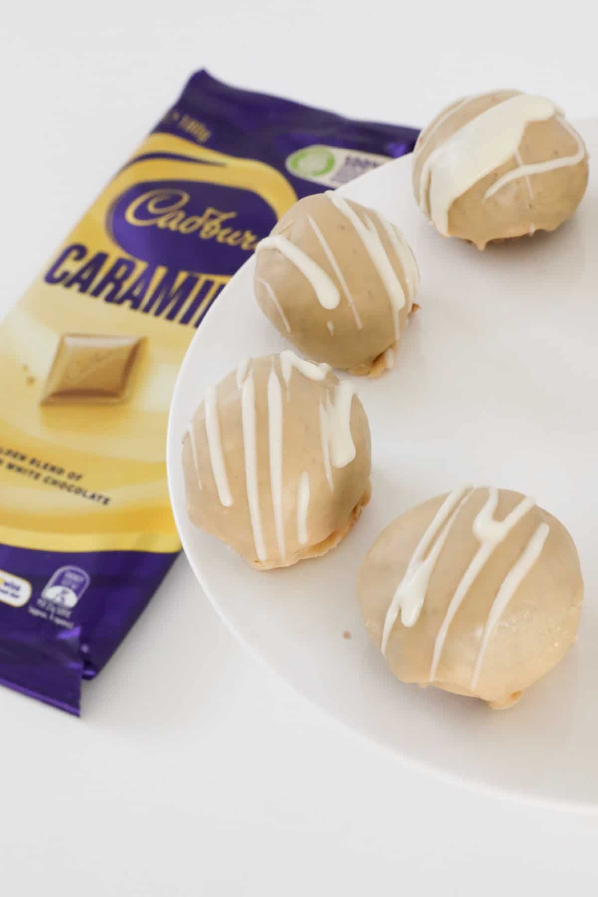 A close up of Caramilk Cheesecake balls with a block of Caramilk chocolate beside.