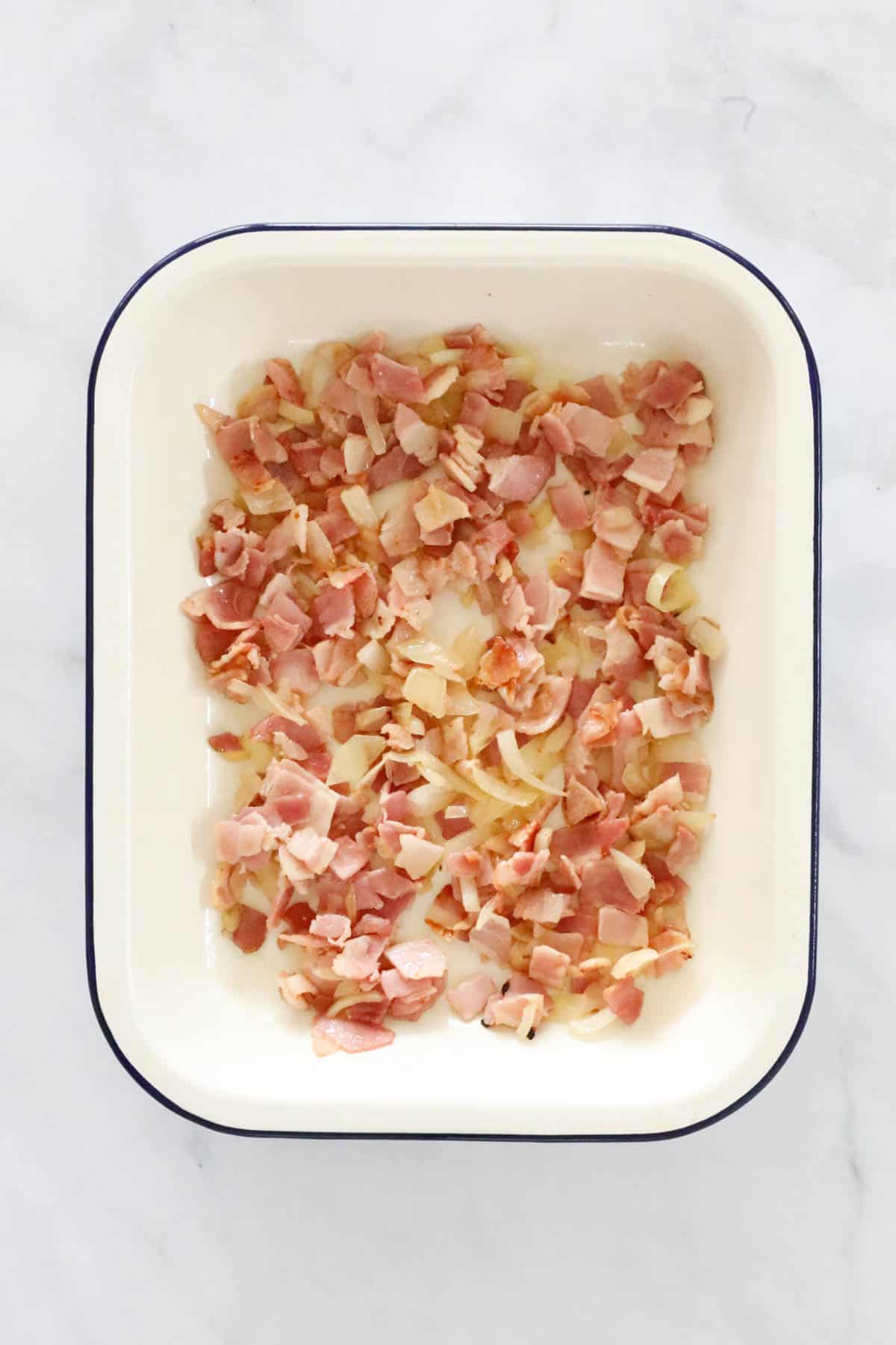 Diced and sauteed bacon and onion in an enamel casserole dish.