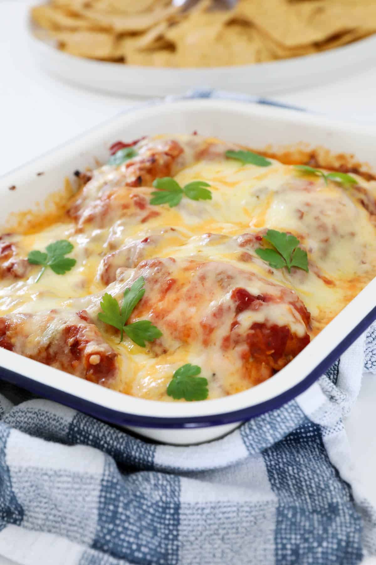 A baking dish filled with spicy salsa chicken with melted cheese on top.