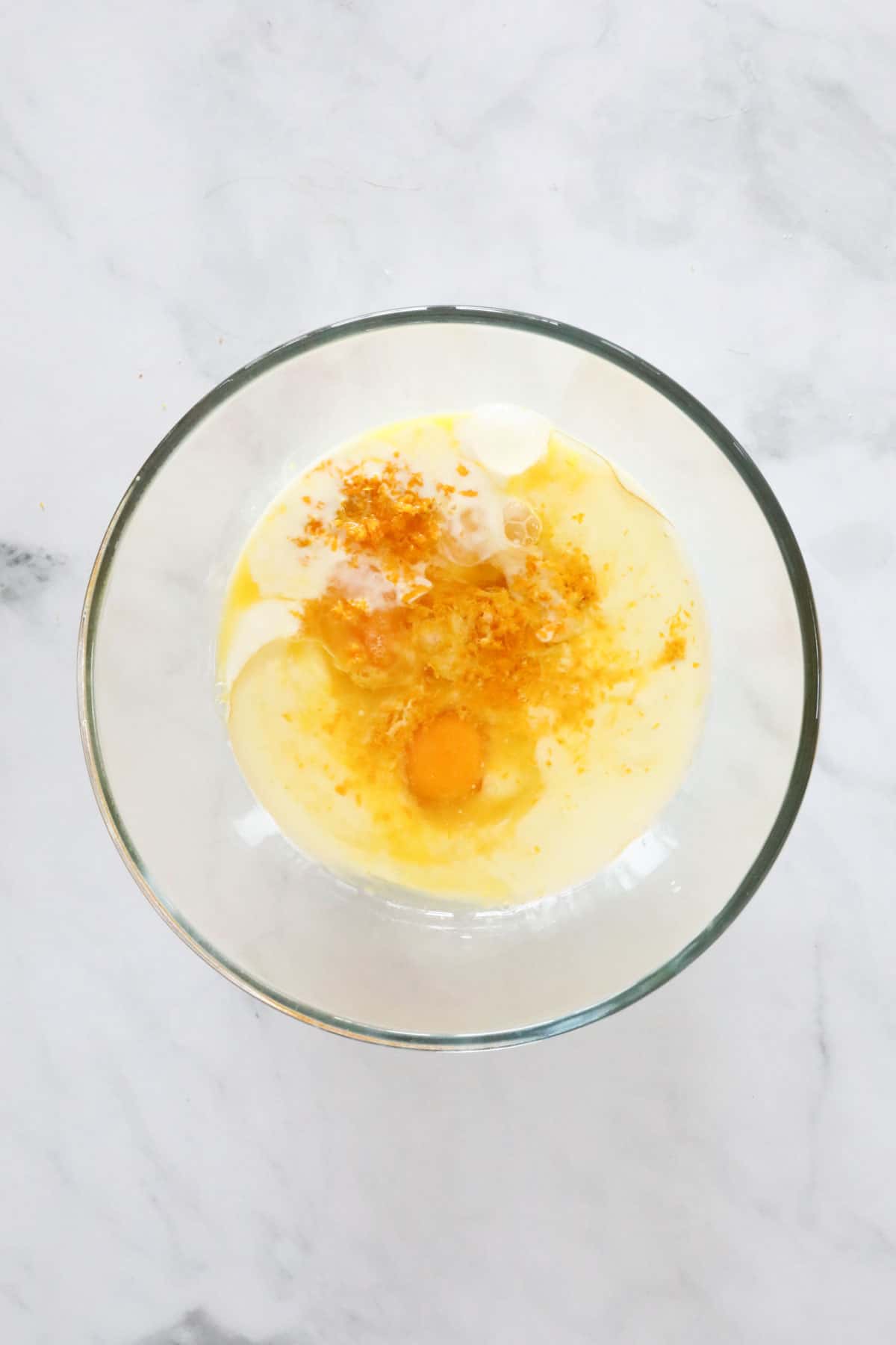 Wet ingredients - oil, buttermilk, zest, juice and eggs in a glass bowl.