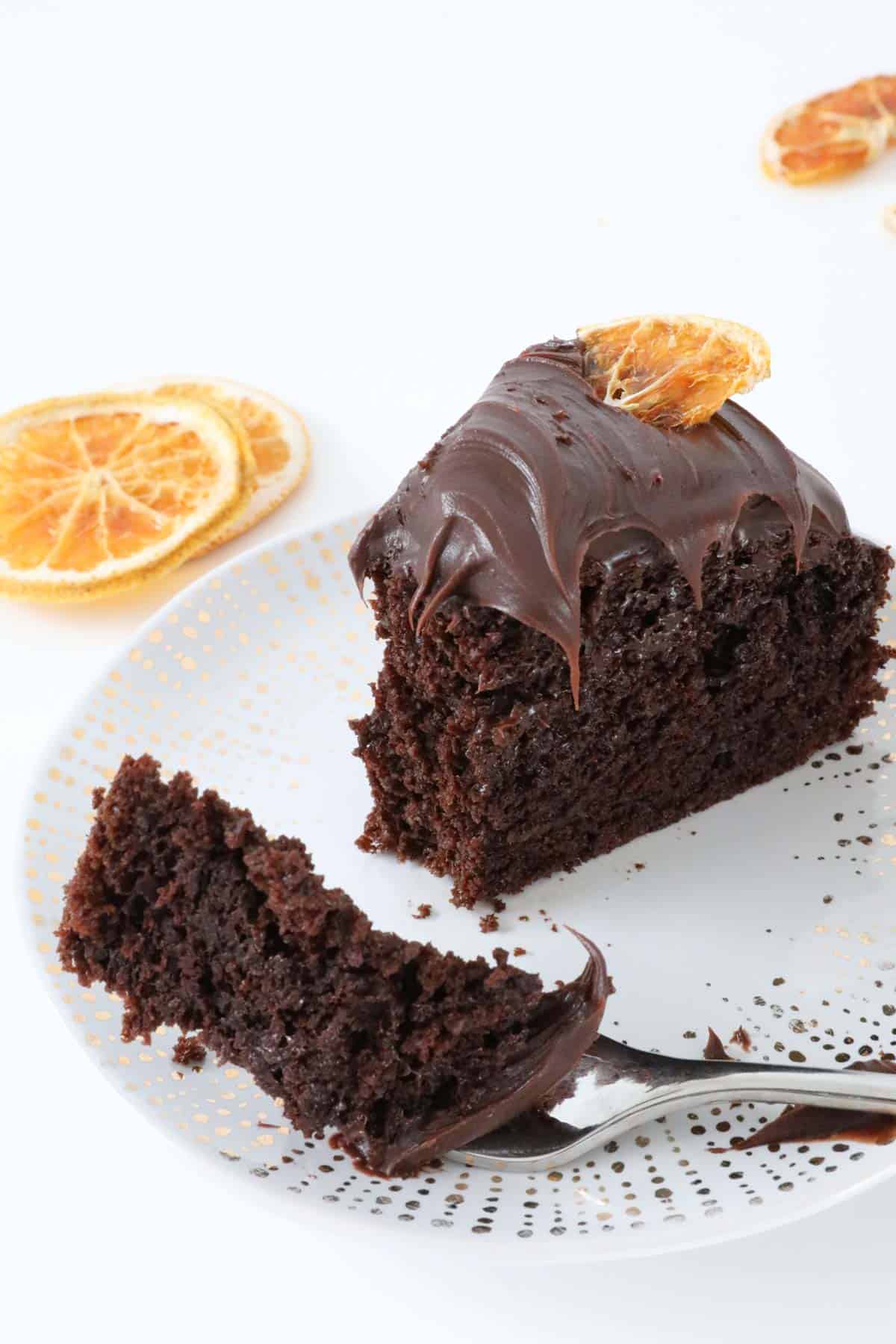 A slice of dense chocolate cake topped with ganache and dried orange slices.