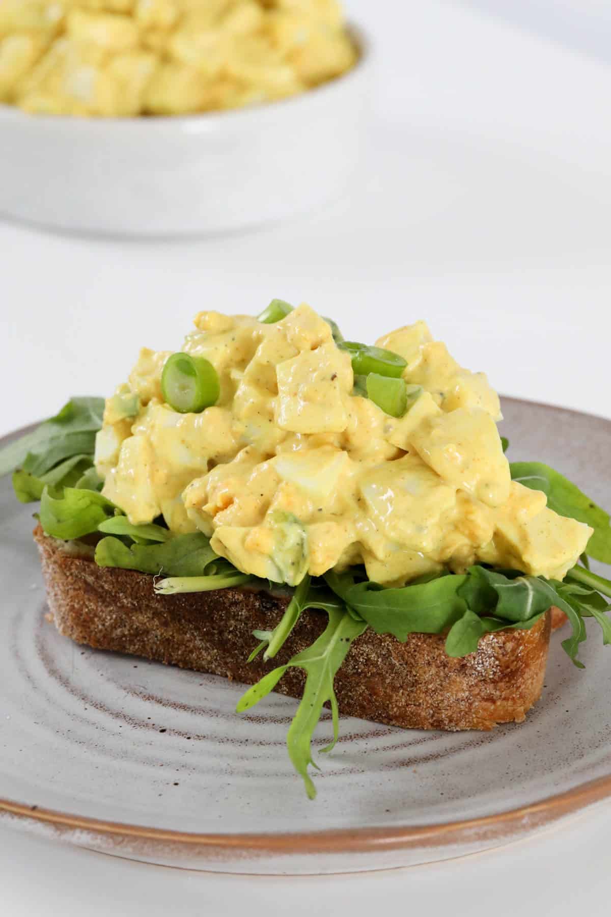 Curried egg salad on a bed of lettuce on top of a slice of rye bread.