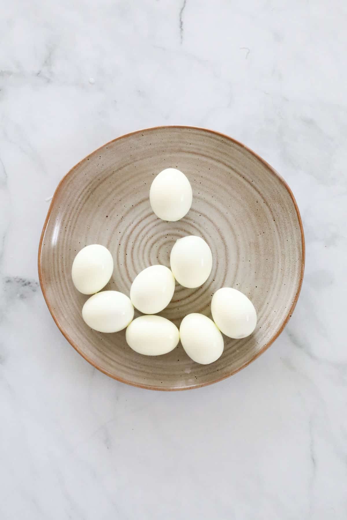 Peeled hard boiled eggs in a bowl.