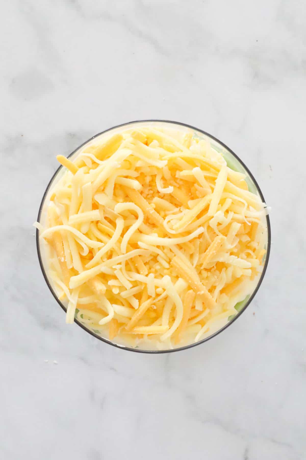 Looking down on a dip bowl topped with grated cheese.