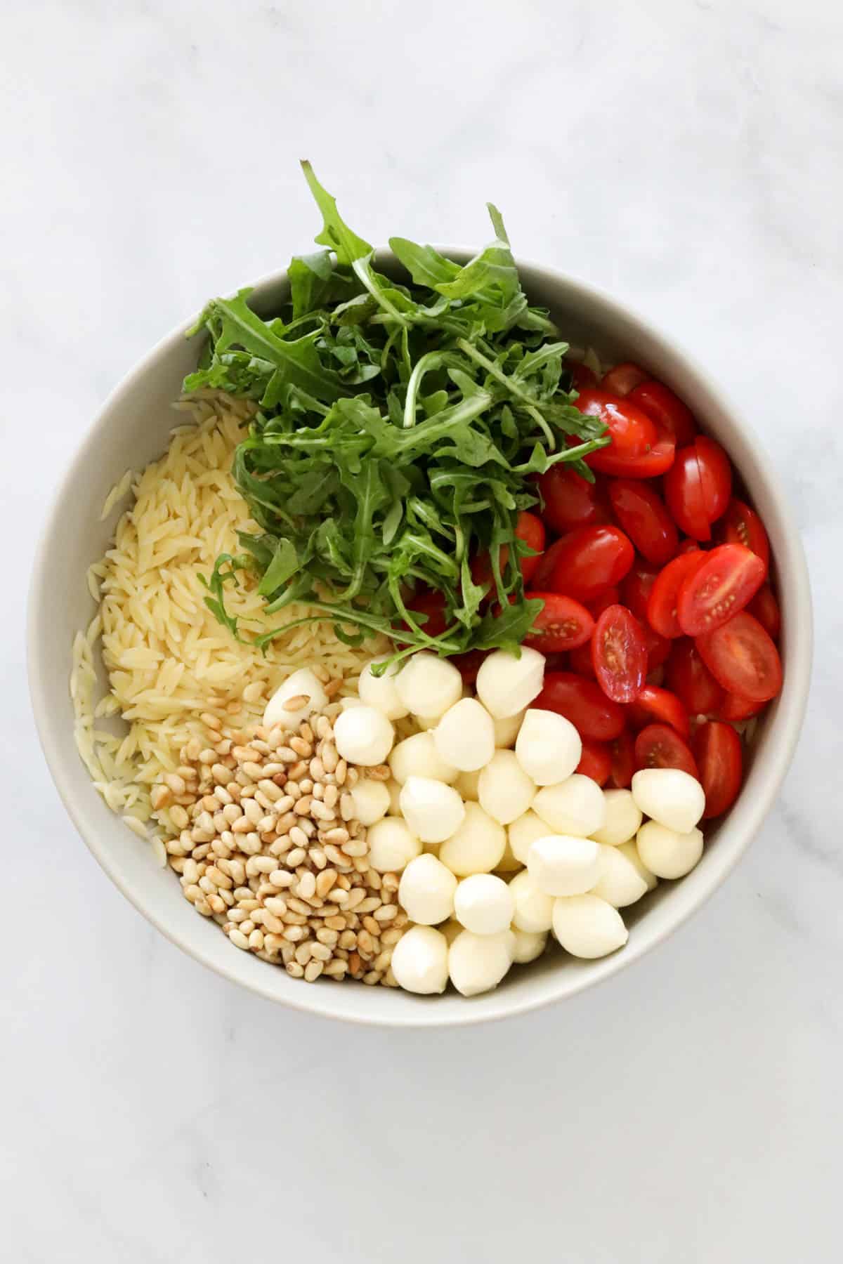 All ingredients for orzo salad in a bowl before being combined.