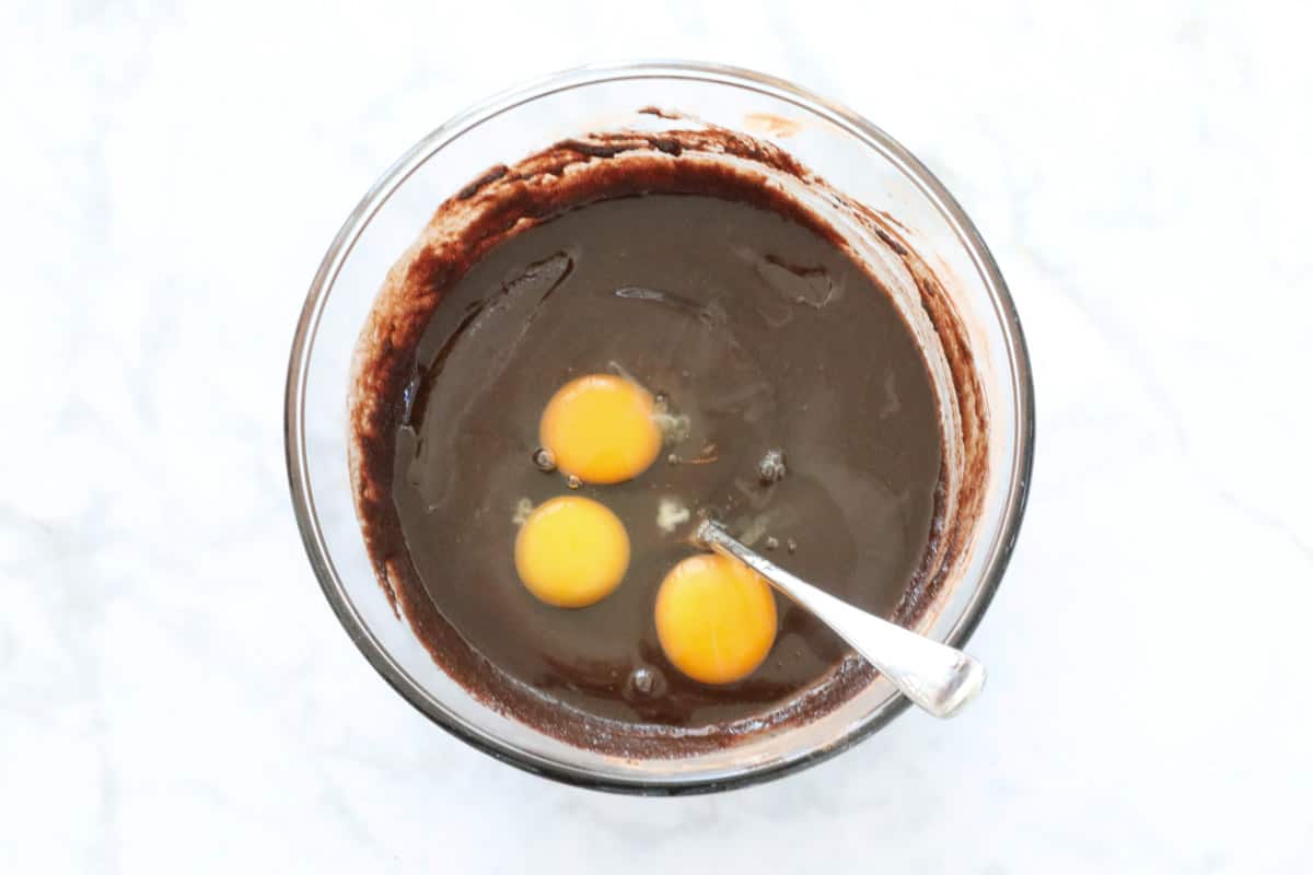 Eggs added to chocolate mixrure in a bowl.