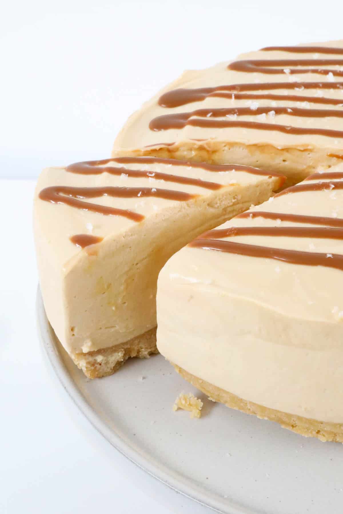 Sliced salted caramel cheesecake drizzled with caramel sauce on a plate.