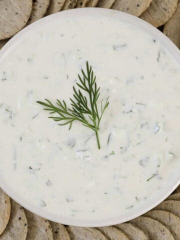 An overhead shot of a bowl of Greek dip with fresh dill on top.