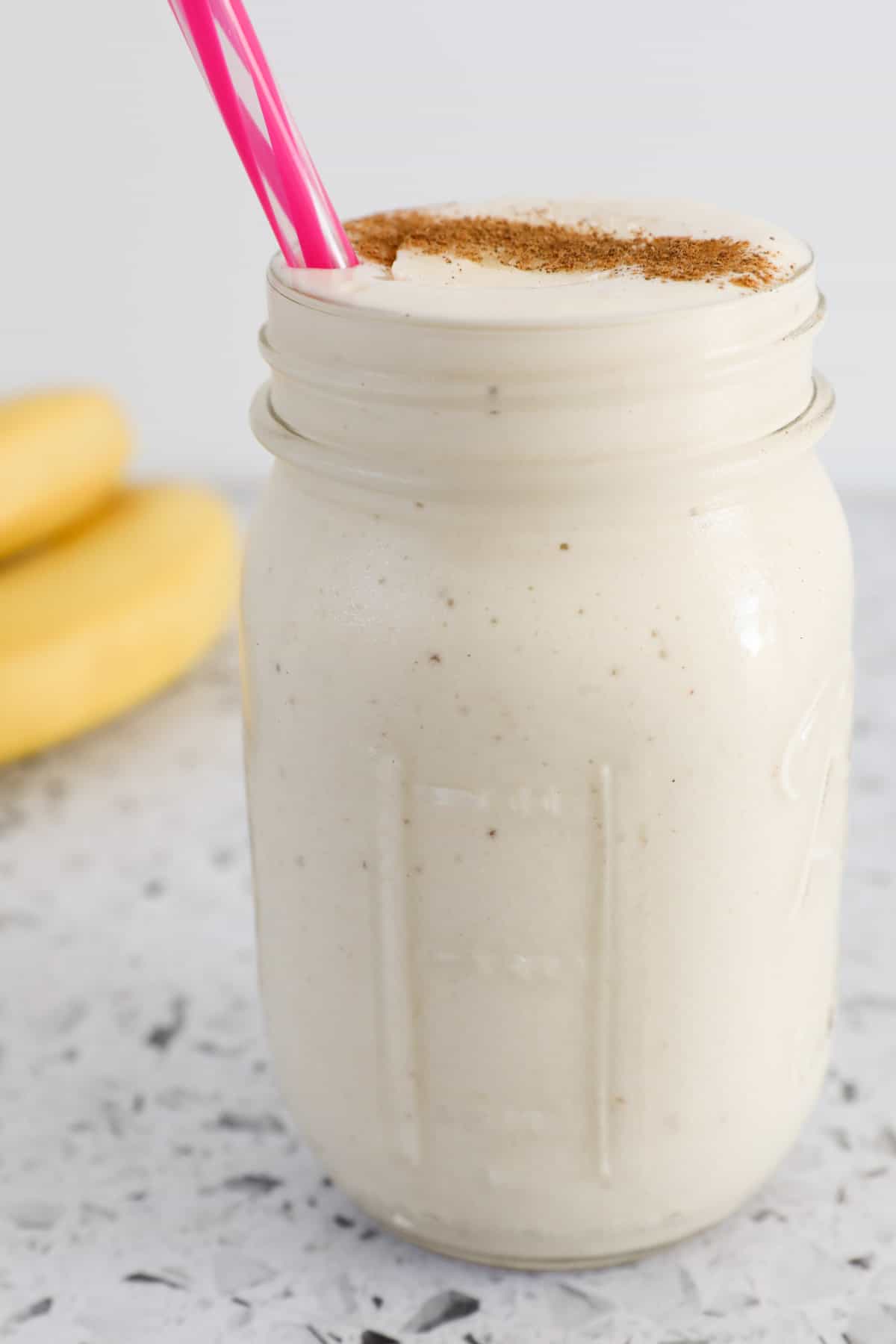 A glass jar filled with a thick and creamy banana milkshake.