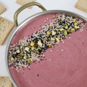 A bowl of colourful beetroot dip sprinkled with dukkah.