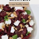 A colourful beetroot salad with feta. walnuts and mint leaves in a white dish.