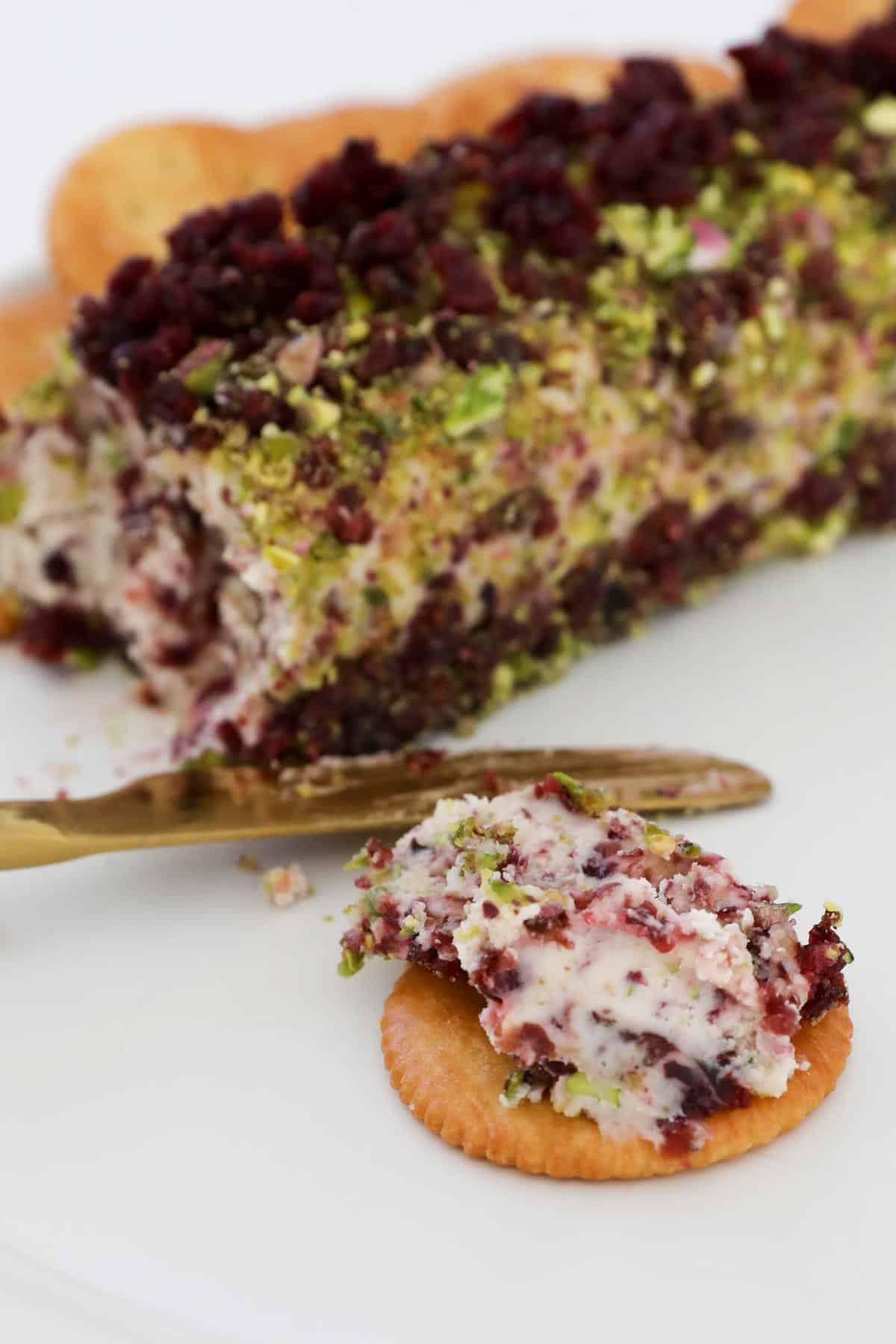 Cranberry pistacho cheese log spread on a cracker.