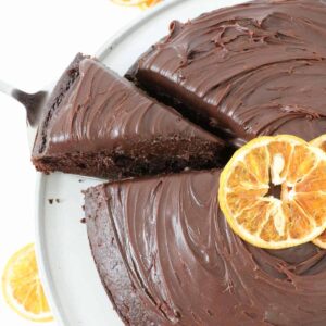 An overhead shot of a pieceof chocolate ganche cake with oranges being removed from the cake.