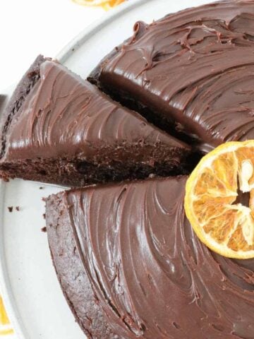 An overhead shot of a pieceof chocolate ganche cake with oranges being removed from the cake.
