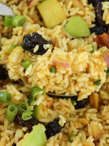 A spoonful of mild curried rice salad with nuts and raisins.