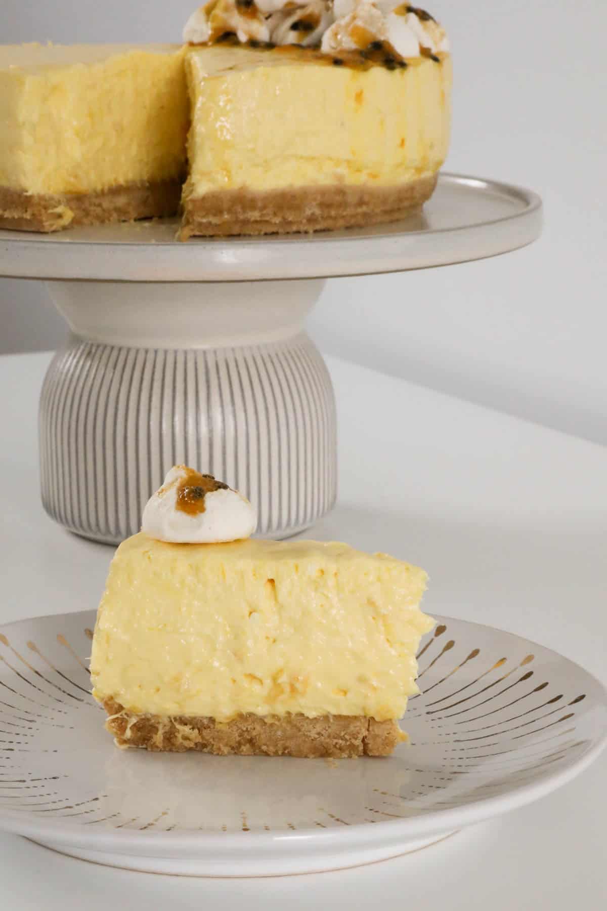 A creamy dessert on a cake stand with a slice on a plate.