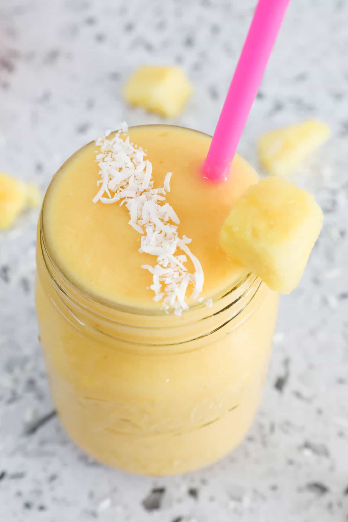 A creamy breakfast fruit drink in a glass jar with a straw.
