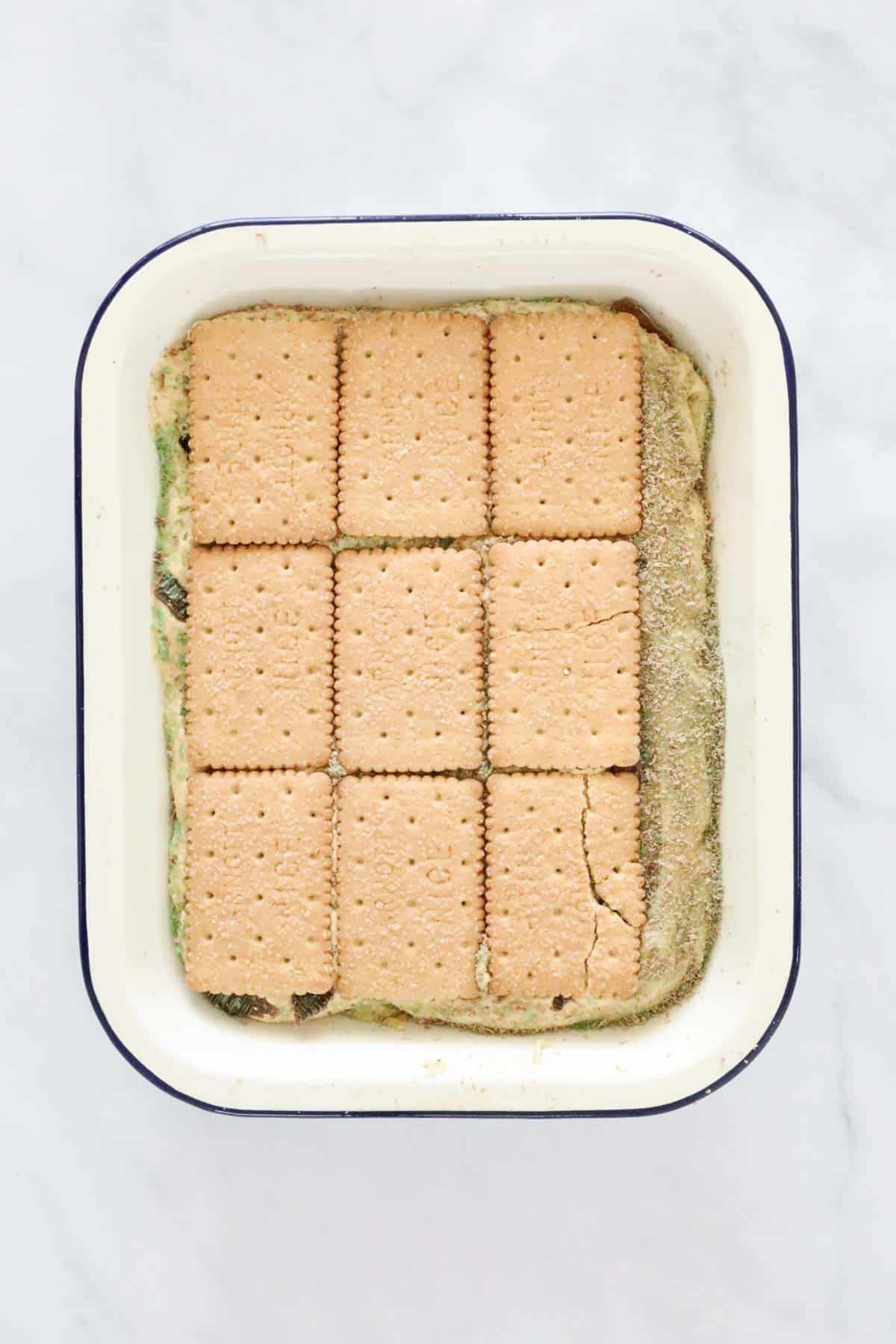 Biscuits layered on top of cream mixture in a baking dish.