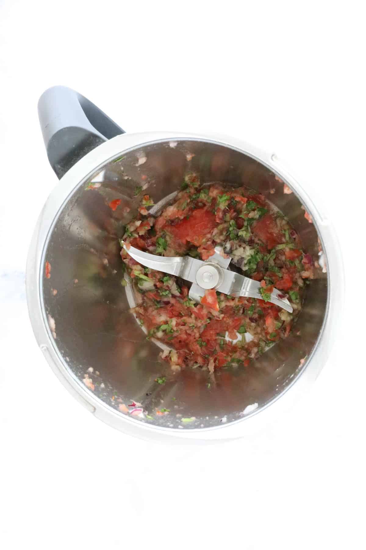 Chopped tomato and herbs in a Thermomix.