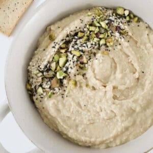 An overhead shot of a bowl of hummus with crushed pistachios on top.