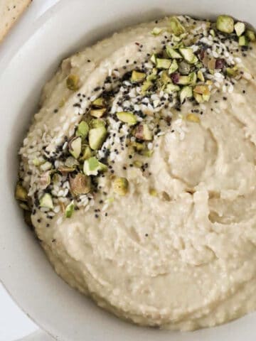 An overhead shot of a bowl of hummus with crushed pistachios on top.