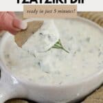 a cracker being dipped in a bowl of Tzatziki dip.