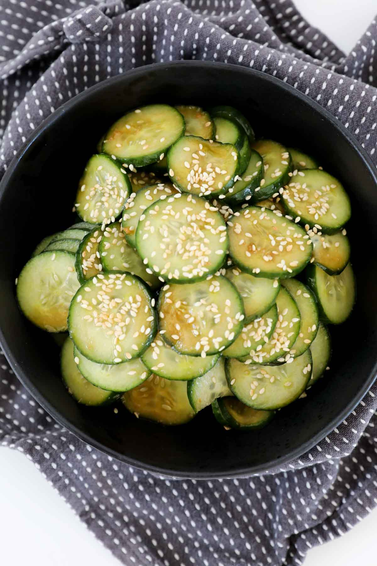 Cucumber salad sprinkled with toasted sesame seeds in a serving dish.