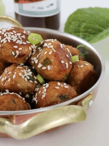 A bowl filled with turkey meatballs coated in hoisin and soy sauce.