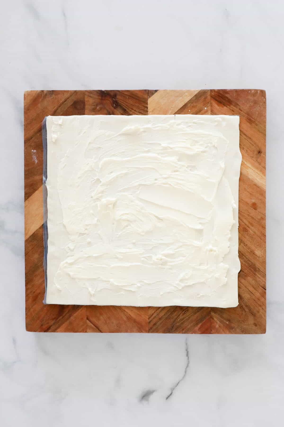 Cream cheese spread on a sheet of puff pastry.