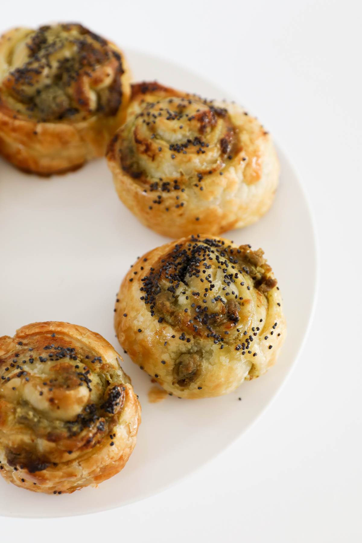 Four flaky pastry pinwheels on a plate.