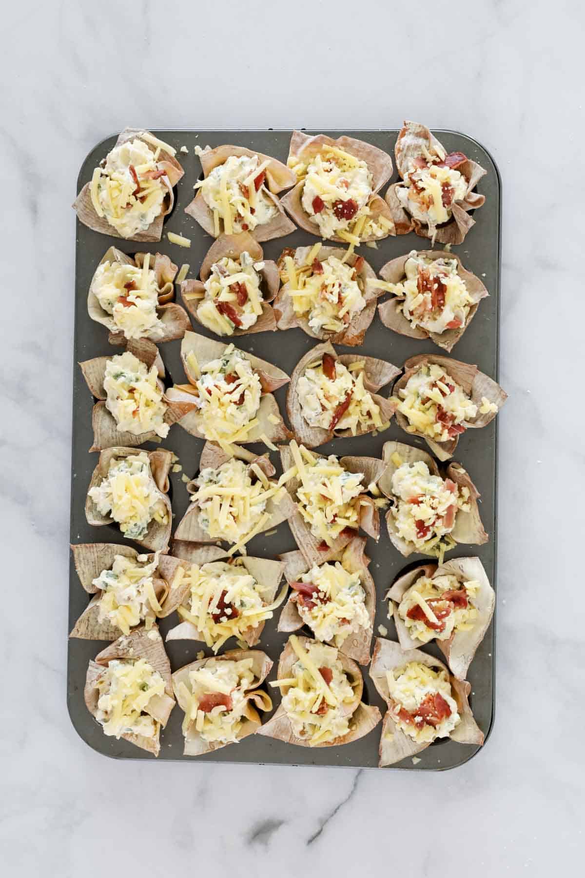 Unbaked spicy jalapeno wonton cups on a baking tray.