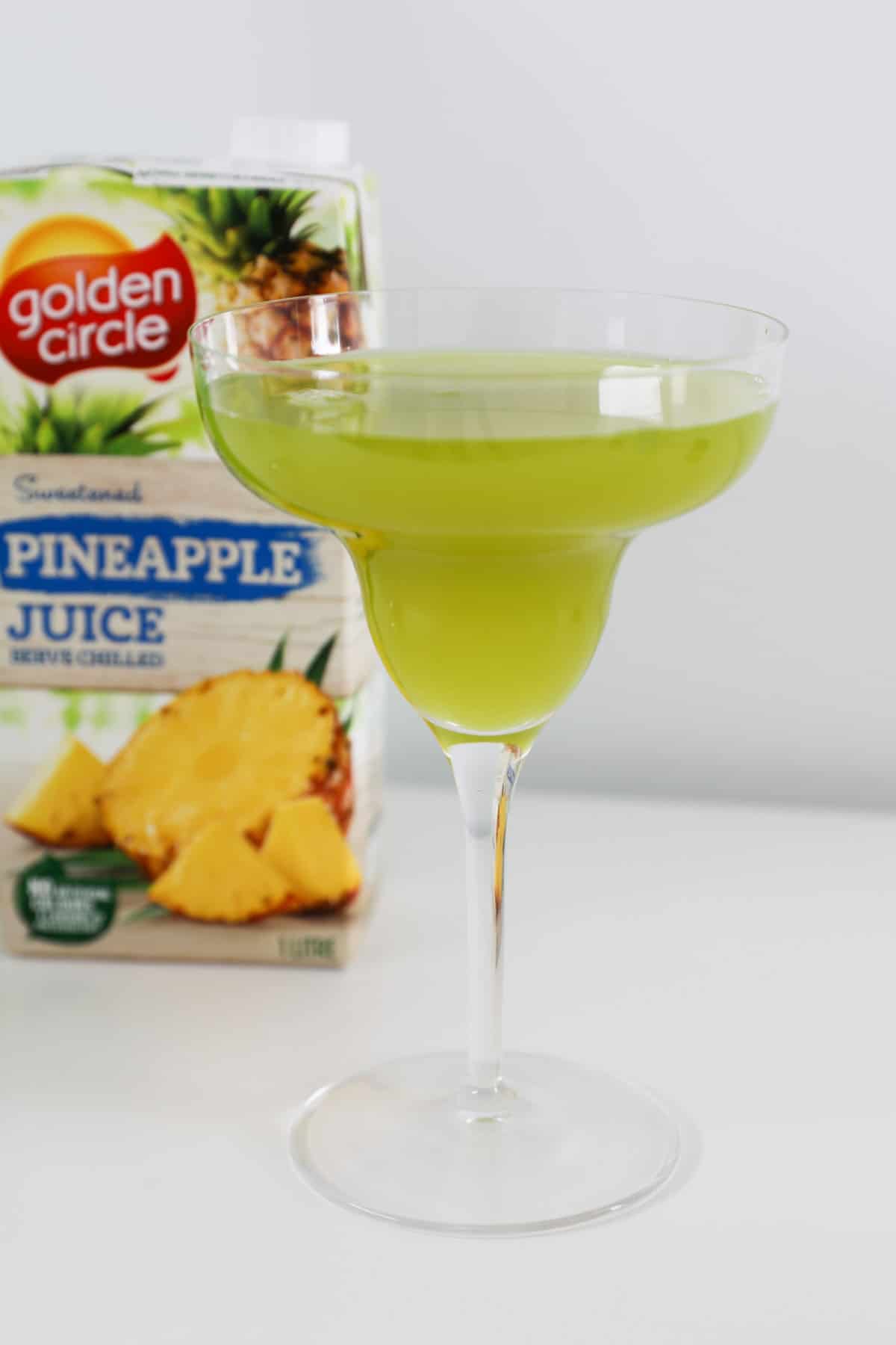 Pineapple juice behind a green cocktail.